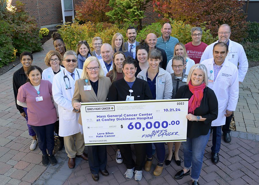 A group of Cooley Dickinson staff holding a large donation check