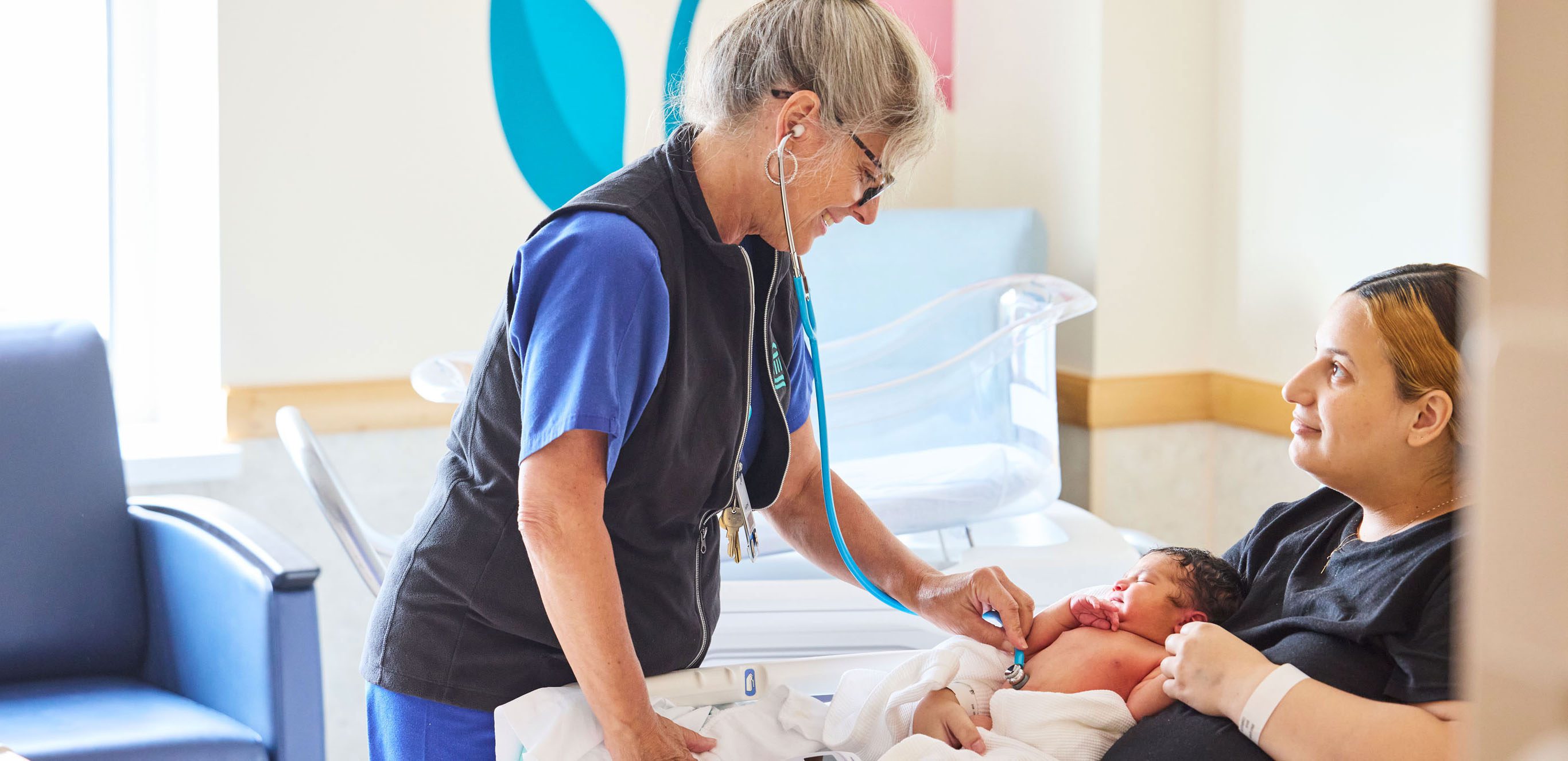 Female nurse tending to a patient and her newborn.