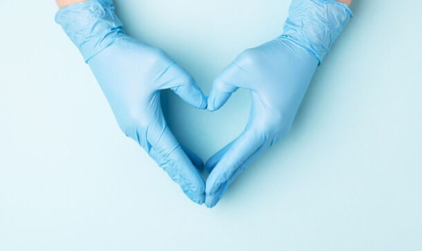 Two hands in surgical gloves forming the shape of a heart